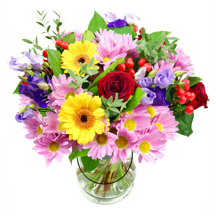 This photograph captures a generous, expertly composed bouquet that seems to glow against its white background, as if lit by soft daylight streaming through a terrace window in Earls Court. The flowers are gathered into a clear glass vase that reveals a fan of carefully trimmed stems, their clean lines echoing the arrangement's polished finish. At the heart of the bouquet, deep red roses open in velvety, layered whorls, providing emotional depth and an unmistakable sense of romance. Framing these roses are two cheerful yellow gerbera daisies with distinctive brown-orange centres, their open, round faces sending out rays of bright colour that feel uplifting and modern. Encircling this central cluster is a cloud of pink daisies or chrysanthemums, each bloom made of fine petals radiating from a small yellow centre, lending softness and a friendly, informal charm, like a smile in floral form. Interlaced through the pink are lisianthus blossoms in tones of purple and lavender, their bell-shaped flowers with gently crimped edges adding cool contrast and a more refined, sophisticated note. Bright red hypericum berries tuck between stems and petals, catching the eye with their smooth, rounded shapes and injecting a hint of playful texture. A mix of foliage in varying greens-some leaves broad and dark, others more slender and light-frames the blooms and fills the spaces between them, giving the whole arrangement a lush, garden-like presence. The result is a full, rounded bouquet that feels perfect for birthday celebrations, housewarming gifts, or an elegant dining table in a flat off Warwick Road, bringing warmth and colour to any corner of Earls Court.